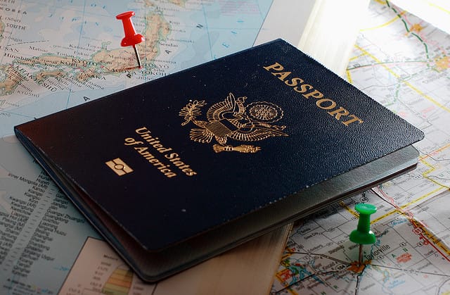A passport and pushpins on a travel map, for timeshare travel beyond one resort.