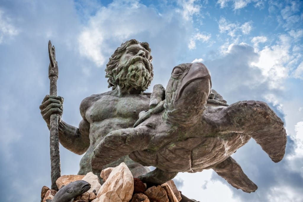 King Neptune statue holding a trident and sea turtle on the Virginia Beach boardwalk, one of the best boardwalks on the East Coast