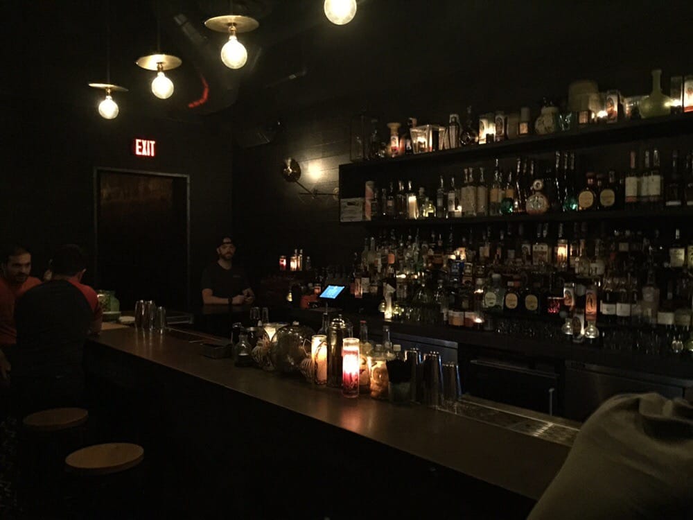 Dimly lit bar with shelves of bottles at Coyo Taco Wynwood