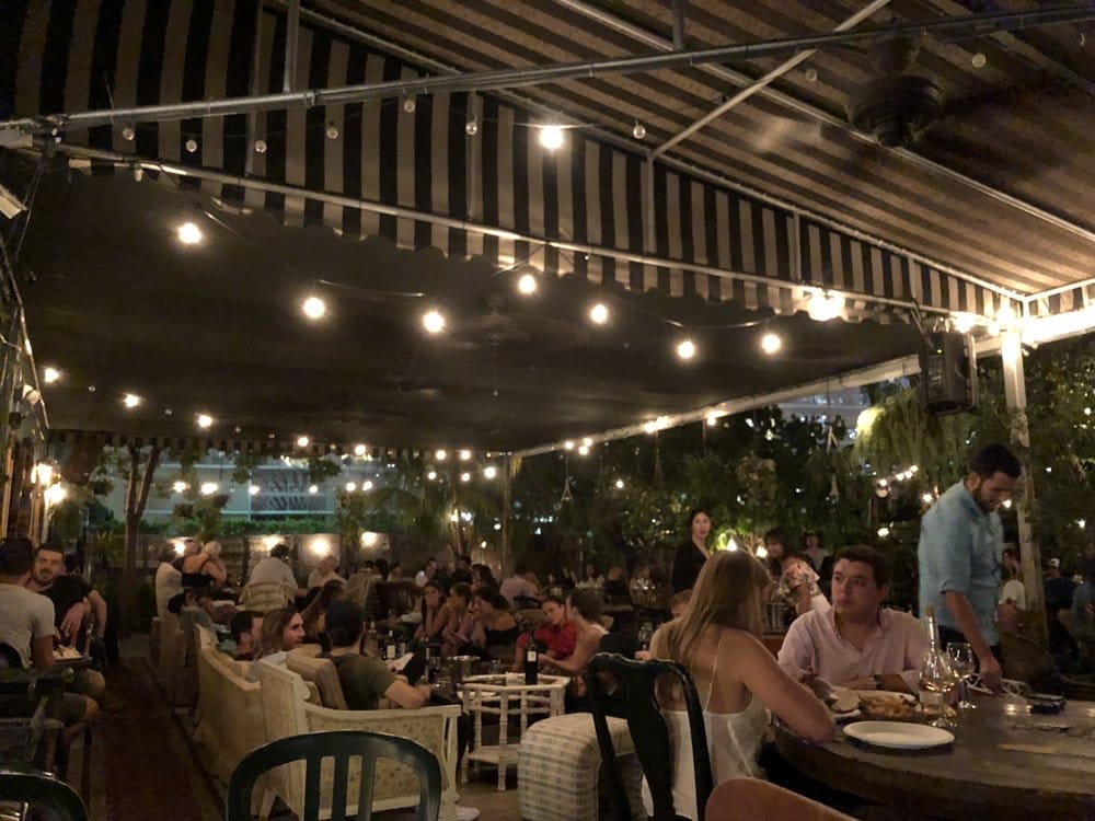 String lights under the striped awning on Lagniappe's patio, one of the things to do in Miami at night