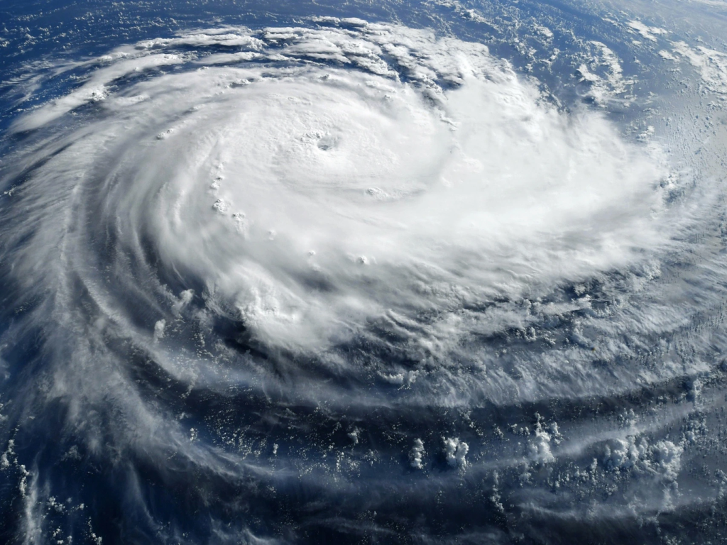 A dramatic satellite view of a large hurricane swirling over the deep blue ocean.