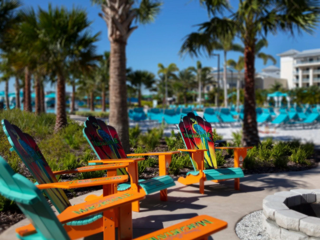 Colorful tropical Adirondack chairs lined up on the sunny pool deck at Margaritaville Resort Orlando.