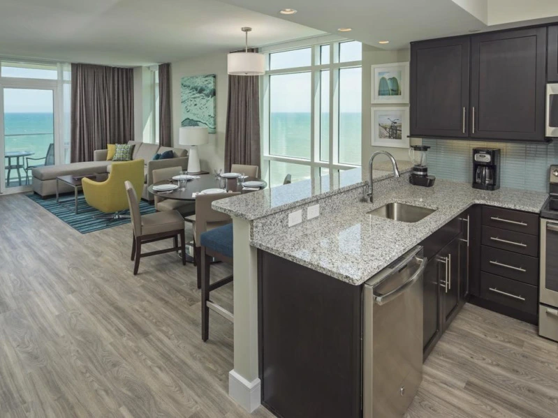 Modern oceanfront kitchen and living area with a balcony view at Ocean 22 by Hilton Grand Vacations.