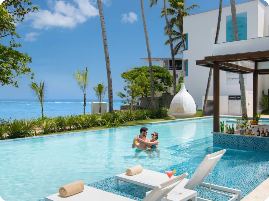 Couple relaxing in a resort pool lined with palm trees