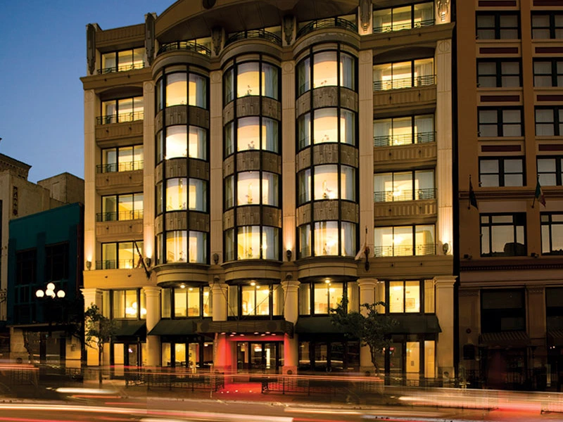 Illuminated multi-story facade and street-level entrance of the historic Harbour Lights timeshare in san diego at night.