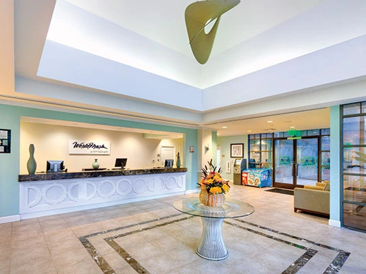 Bright reception desk and spacious lobby area featuring a glass table and modern decor at the WorldMark San Diego Mission Valley resort.