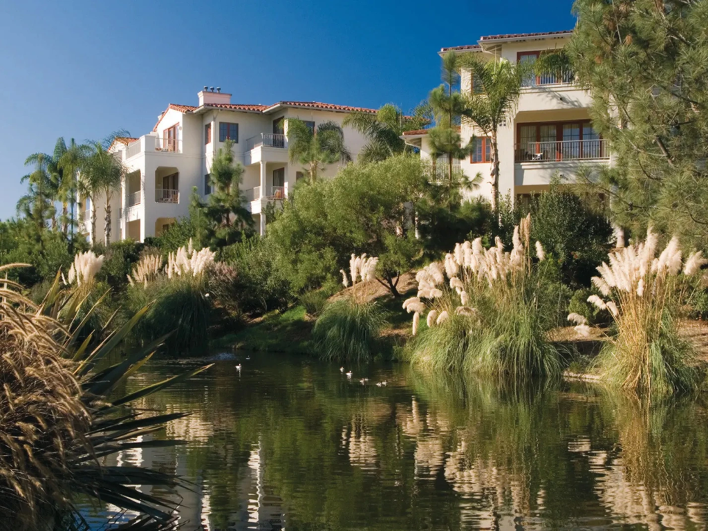 Scenic exterior view of the Four Seasons Residence Club Aviara villas situated alongside a tranquil, natural pond.