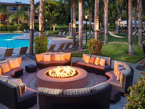 Large outdoor firepit surrounded by comfortable curved lounge seating near the swimming pool at the Hilton Grand Vacations Club MarBrisa resort.