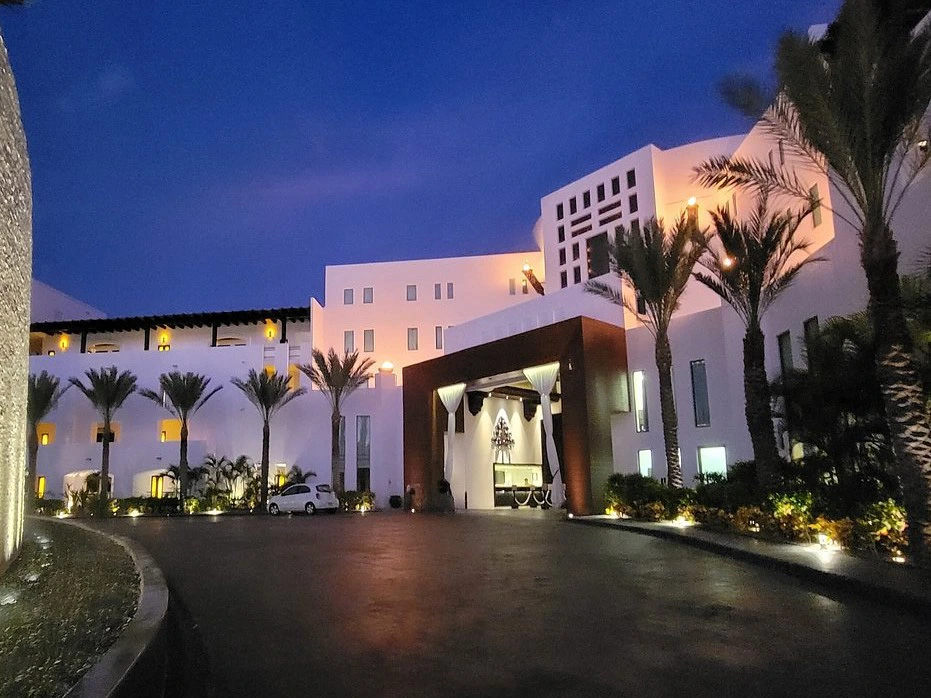 The exterior driveway and white facade of a modern luxury resort illuminated at night.