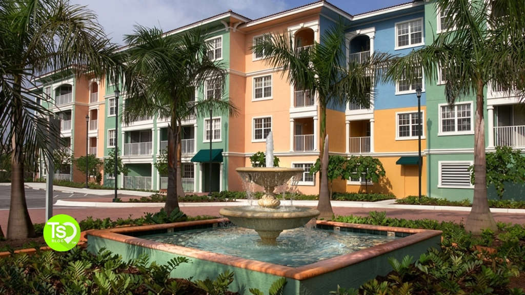 A tiered stone water fountain in front of the colorful resort facade at Mizner at Weston.