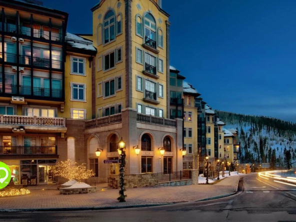 Illuminated luxury resort exterior at dusk with car light trails on an adjacent winding road.