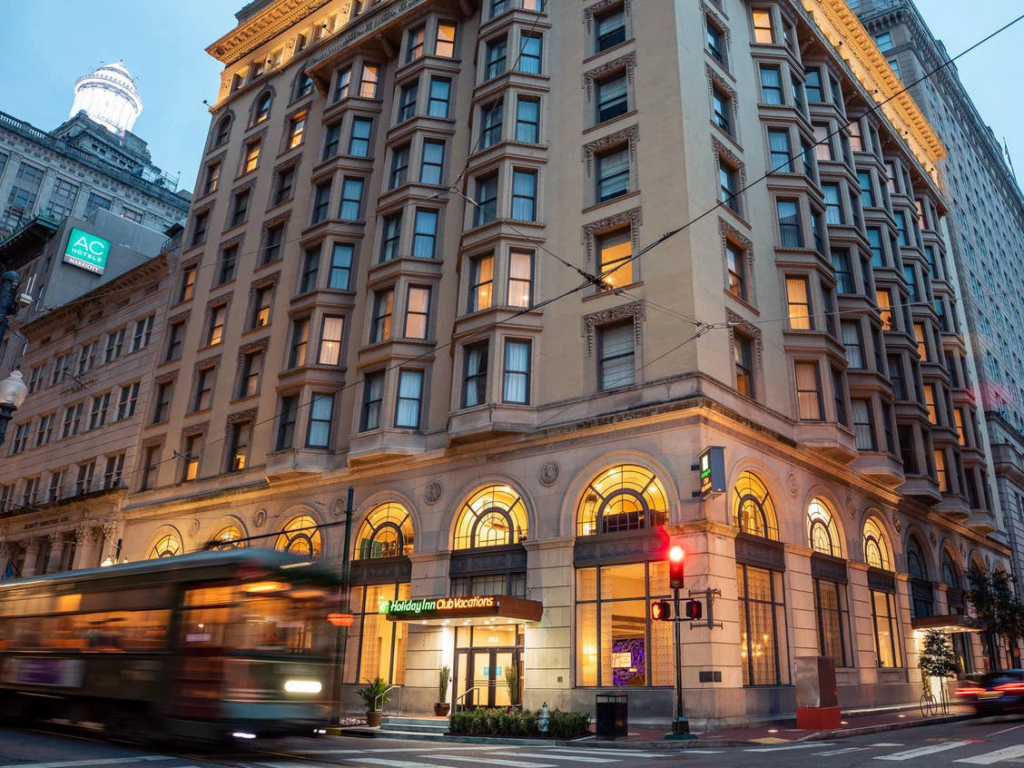 A blurry streetcar passes the historic New Orleans Resort building at dusk.