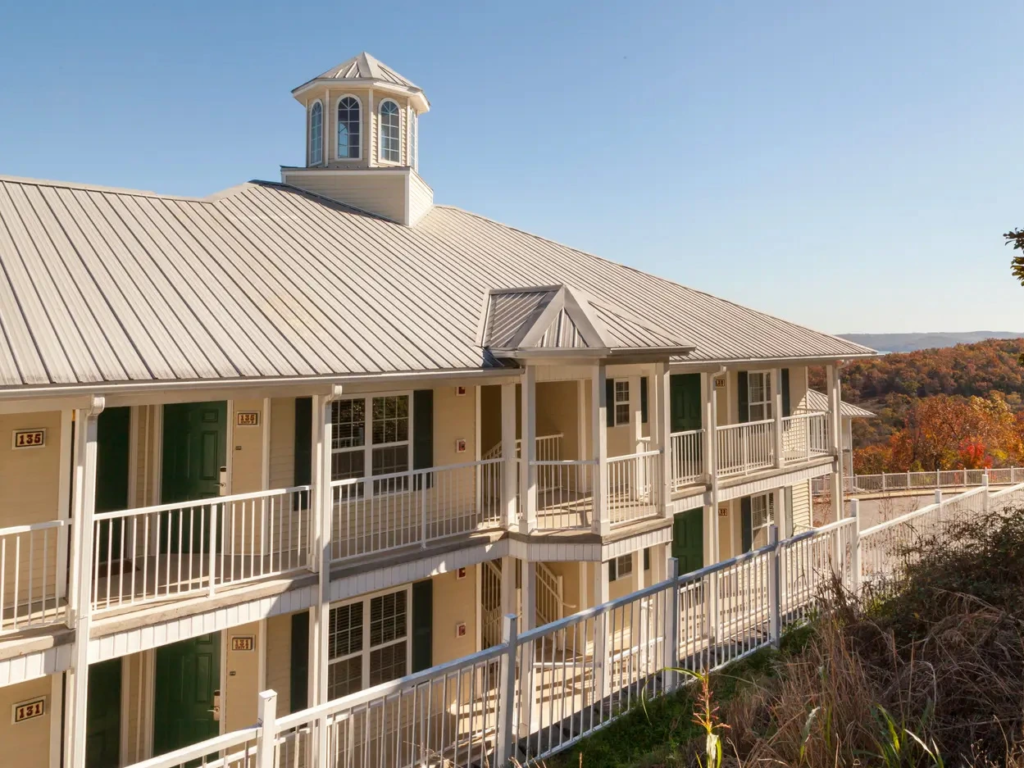 Exterior of the two-story Ozark Mountain Resort building with balconies overlooking a scenic, hilly landscape.