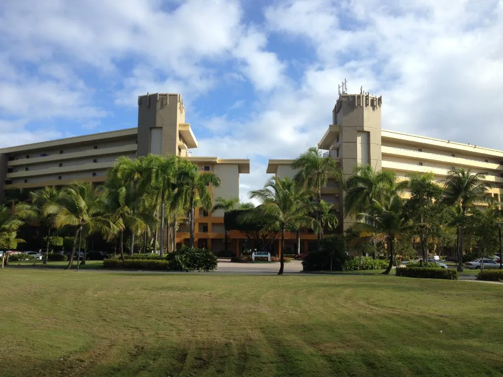 Lush palm trees and manicured lawns frame a two-wing hotel