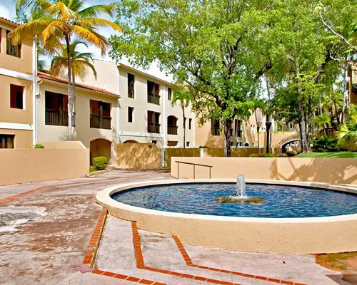 Palm-lined courtyard with a circular fountain at an RCI resort in Puerto Rico, framed by cream stucco buildings.