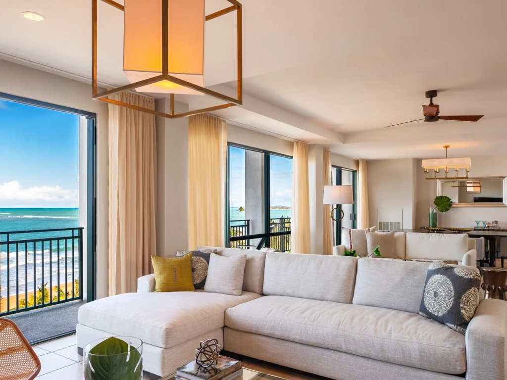 Sunlit living room with ocean-view balcony and open dining area at RCI resorts in Puerto Rico.