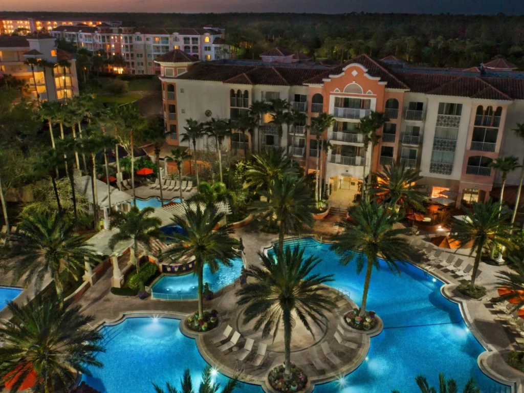 Aerial dusk view of the lagoon pool at Marriott's Grande Vista in Orlando, ringed by palms and lit Mediterranean-style buildings.