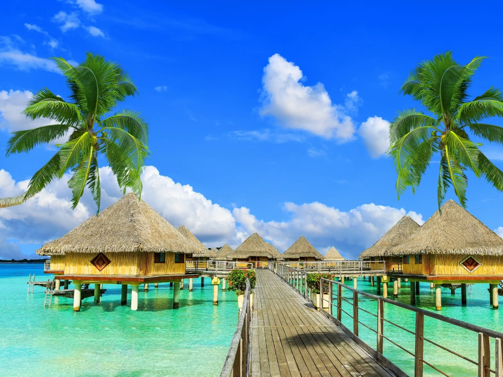Overwater bungalows above a turquoise lagoon offer dreamy Romantic Getaways beneath a clear blue sky.