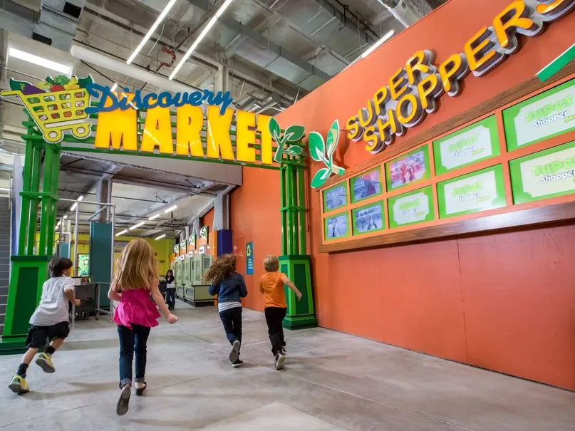 Four children running toward a kid friendly Los Angeles museum's Discovery Market entrance.