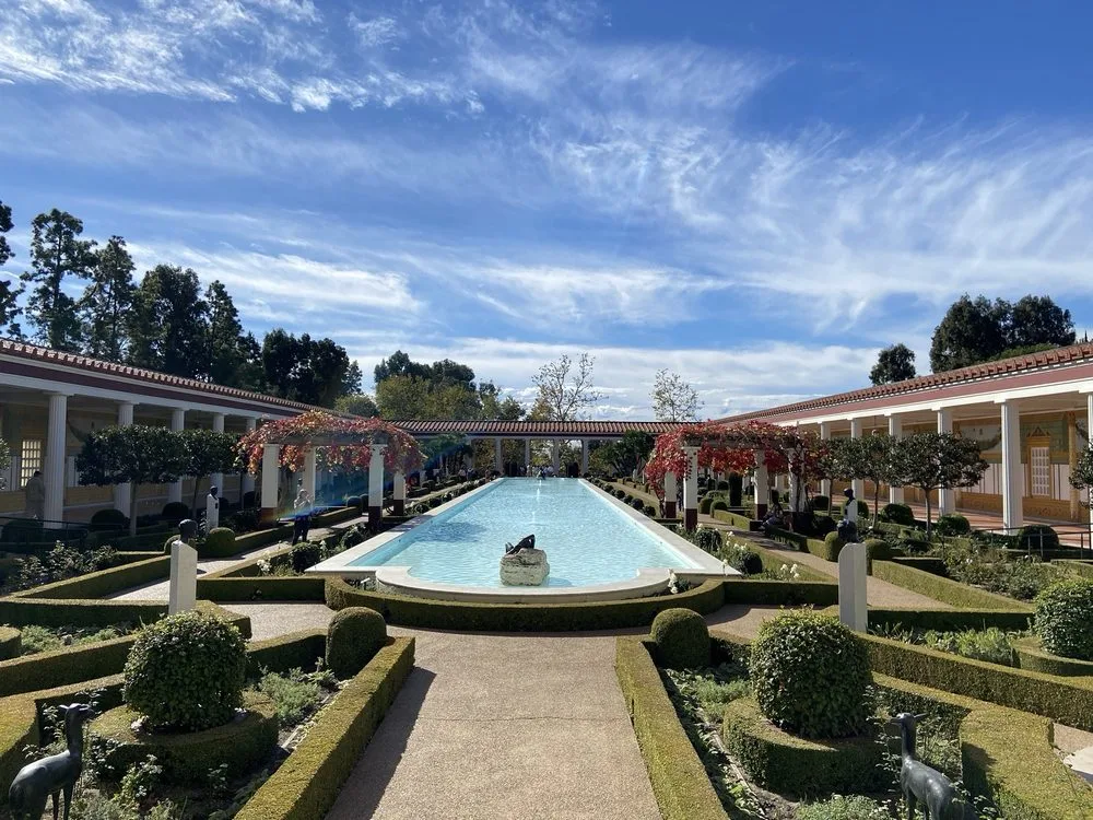 Rectangular reflecting pool and bronze sculptures in the Getty Villa courtyard, a kid friendly Los Angeles cultural destination.