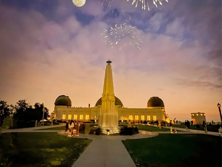 Griffith Observatory at dusk, a kid friendly Los Angeles landmark, with fireworks in a cloudy sky.