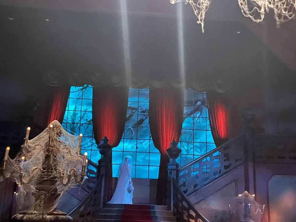 A ghost bride on a staircase inside Phantom Manor, an iconic attraction at one of the best theme parks in the world.