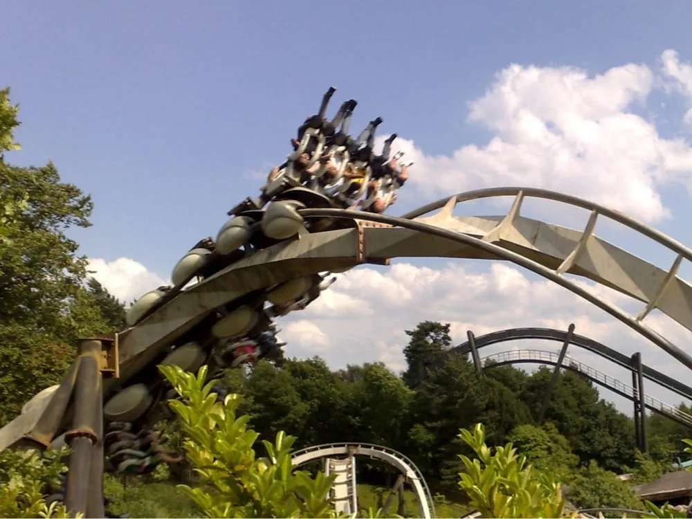 Riders on an inverted coaster curve through lush greenery at one of the best theme parks in the world.