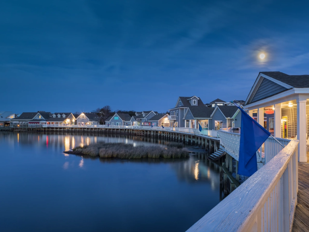 Moonlit wooden boardwalk scene capturing the charm of the best boardwalks on east coast near calm waterfront cottages at dusk.