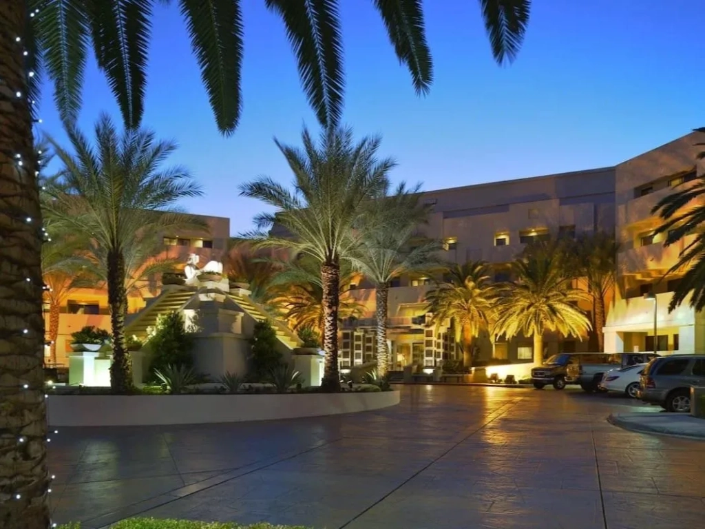 Elegant entrance of vegas timeshare resorts at dusk, with palm trees, warm uplighting, and a tiered fountain.