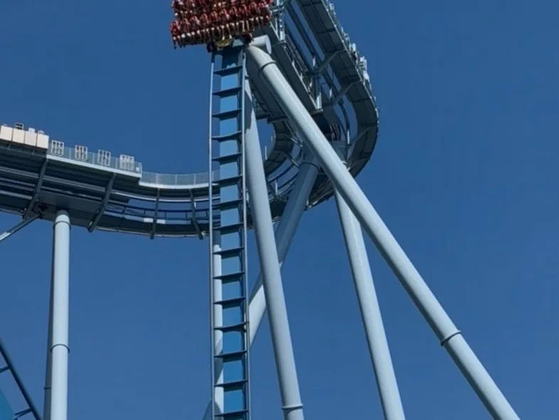 A steel roller coaster cresting a tall lift hill against a clear blue sky at one of the best theme parks in the world.