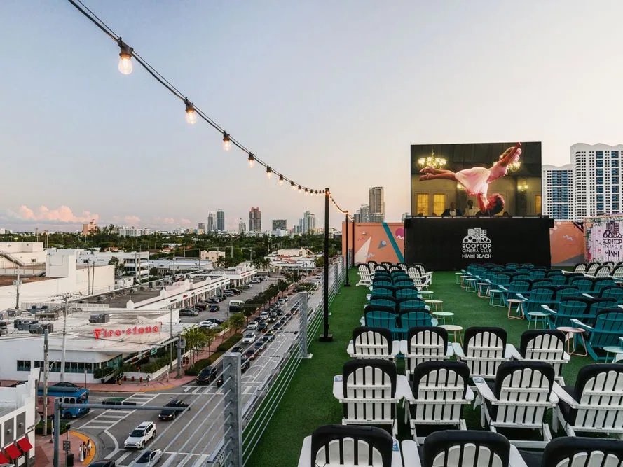Rooftop Cinema Club offers Things To Do in Miami At Night, with Adirondack chairs and a glowing skyline backdrop.