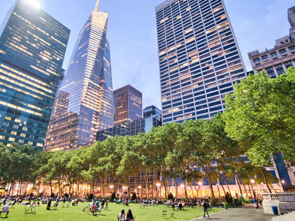 Bryant Park's lawn at dusk, surrounded by Midtown towers