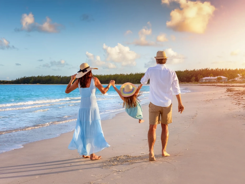 Family walking a beach at sunset, swinging a child between them