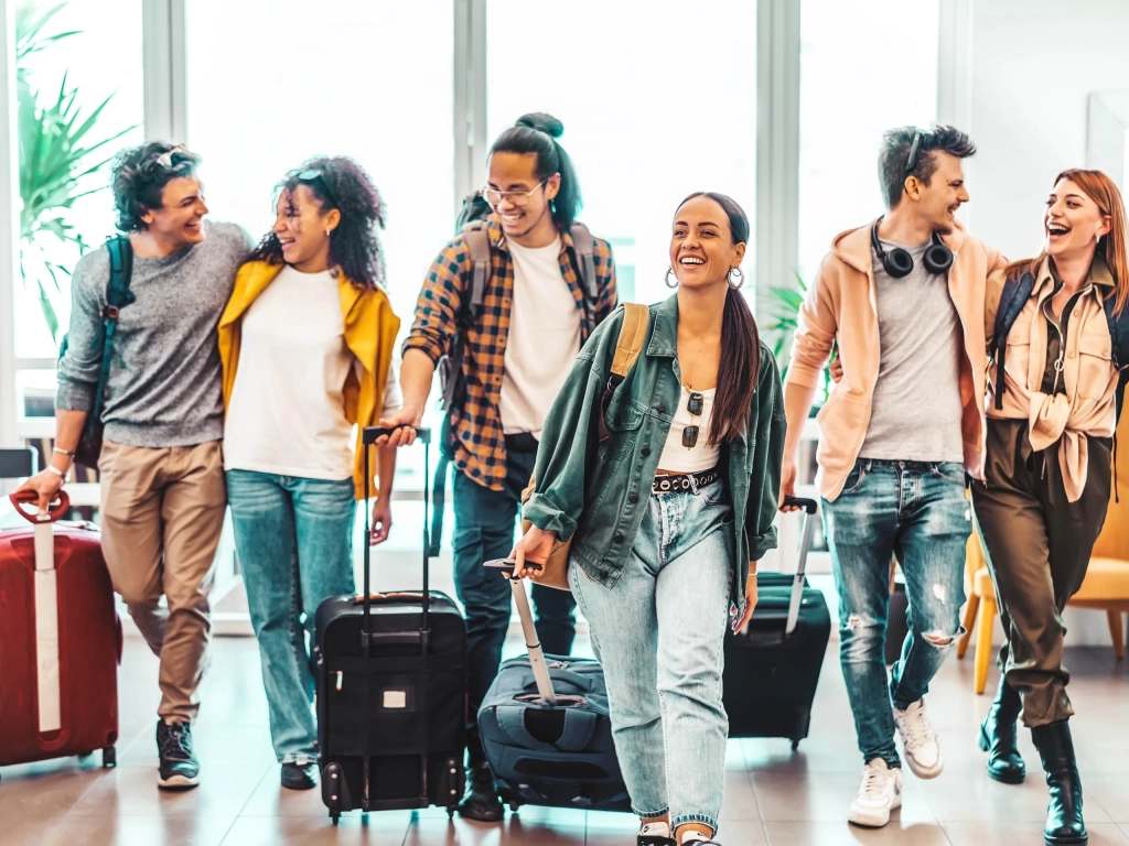 Six friends walking together with rolling suitcases and backpacks