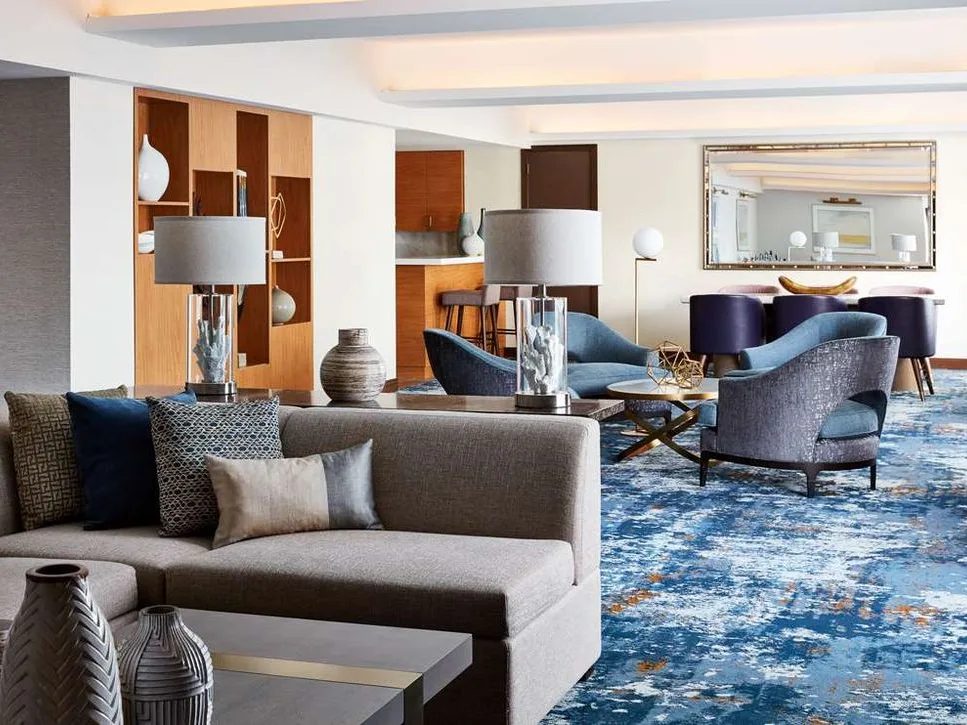 Lounge with a gray sectional and a blue area rug at a Hilton Club in the New York Hilton Midtown